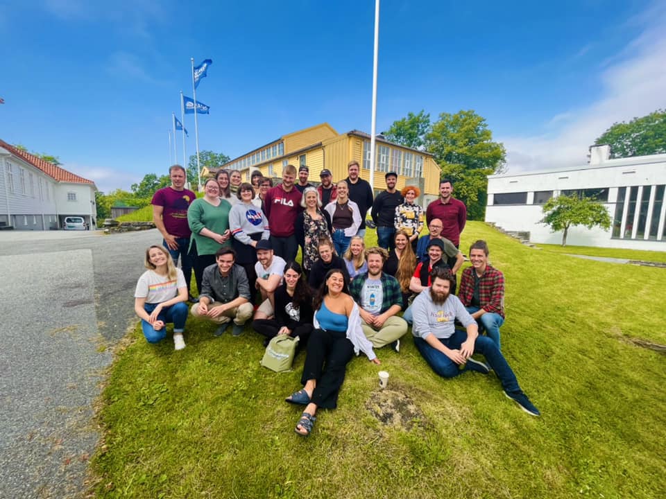 Gruppe smilende menensker i solen fra Fana folkehøgskole 2022.